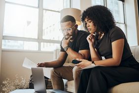 Laptop, paper and couple with mortgage, bills or loans doing financial calculations together at home