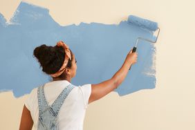 person painting walls of house with blue paint