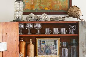 shelves filled with glassware with art hung in it