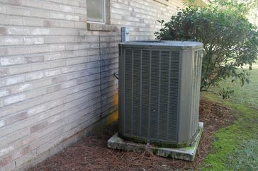 Air Conditioner Compressor near gray brick house