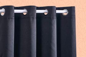 Close-up of black outdoor curtain and rod on an orange background
