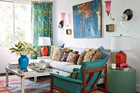 Living room with red lamp, wall sconces, patterned rug and pillows