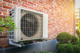 heat pump mounted on brick wall exterior of home 
