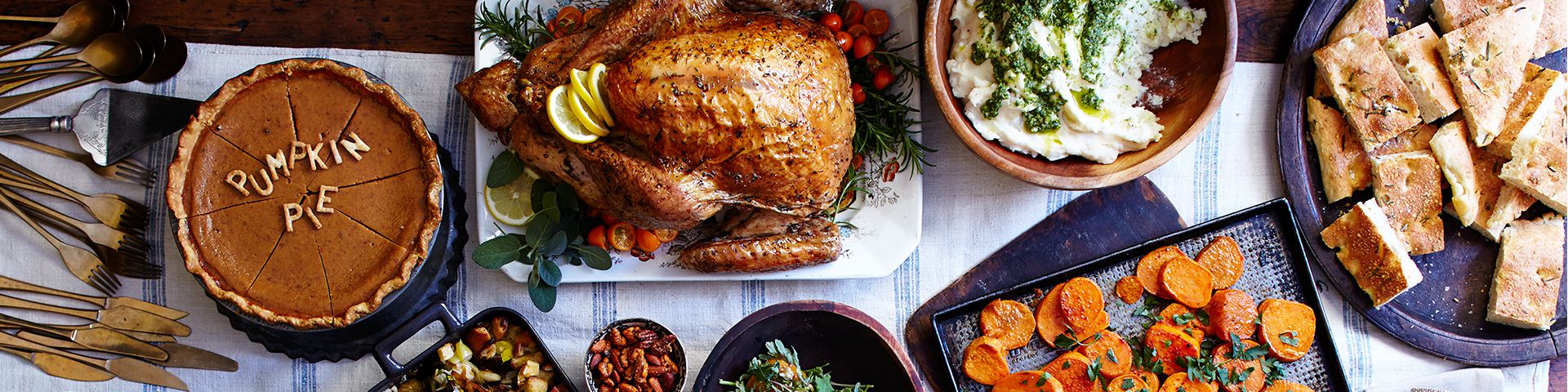 thanksgiving dinner on a table with a pie that says 'pumpkin pie' in crust on top