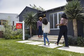 Full length of saleswoman greeting female customers while standing outside house