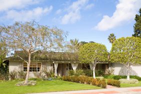 ranch house exterior with plants along front and brick pathway