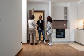 Real Estate Agent Welcoming Clients On Front Door