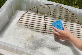 scrubbing dirty grill rack with sponge