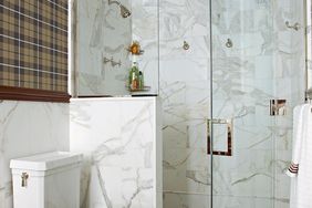 spacious walk-in shower with marble walls and warm tones