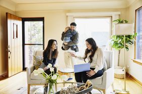 Wide shot of family discussing home for sale with real estate agent