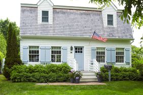 American flag waving on residential building with lawn against sky